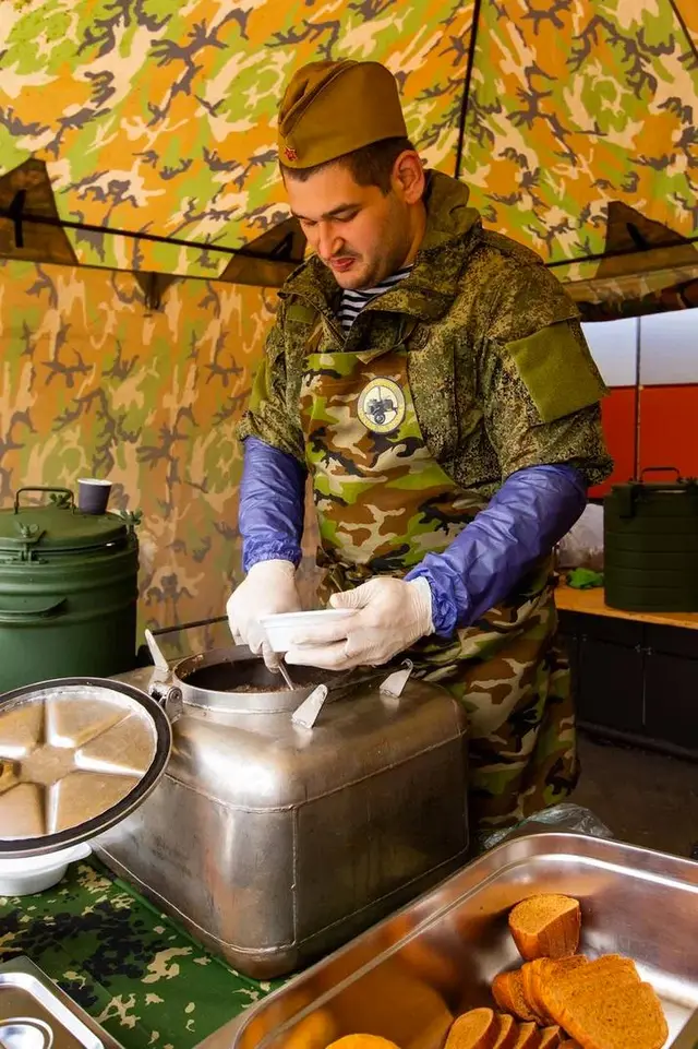 Полевая кухня к 23 Февраля: повар в форме раскладывает солдатскую кашу