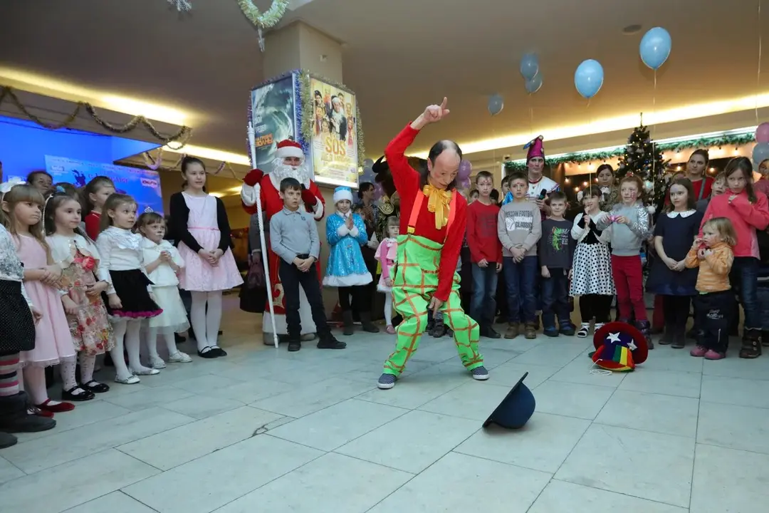 Клоун в зелёных клетчатых штанах танцует перед зрителями