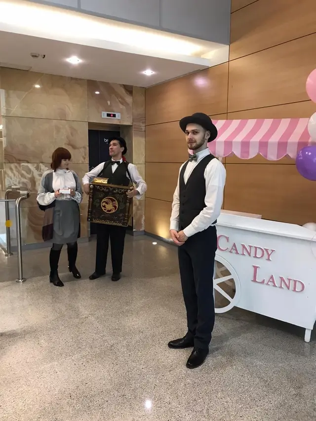 Аниматоры в цилиндрах с шарманкой и тележкой Candy Land в холле