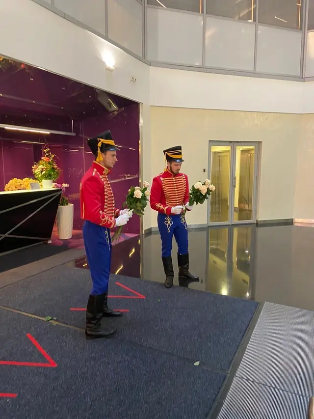 Двое гусар с цветами в холле бизнес-центра